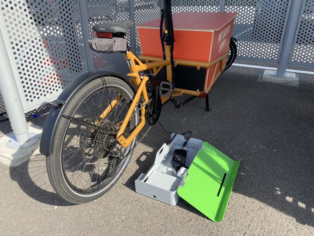 Een longtailfiets staat geparkeerd en wordt opgeladen bij een ALTAO® Cargo VAE-laadpaal in Saint-Lô