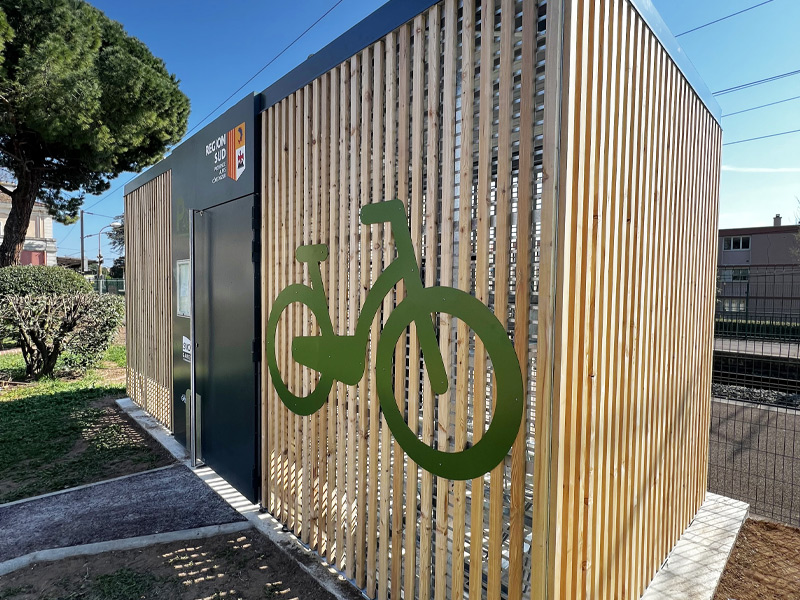 espace de stationnement habillé en barreaudage bois et vélo vert sur local en gare de Fréjus