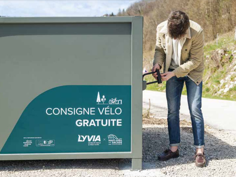 abri vélo individuel ALTAO® Cocoon du haut Jura avec jeune homme qui utilise un antivol en U