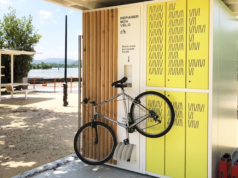 démo d'un vélo sur l'espace de réparation espace de stationnement sécurisé en box pour les vélos, casiers de rangements, station de gonflage et espace de réparation intégrés à la structure de la véloroute du futur à Condrieu