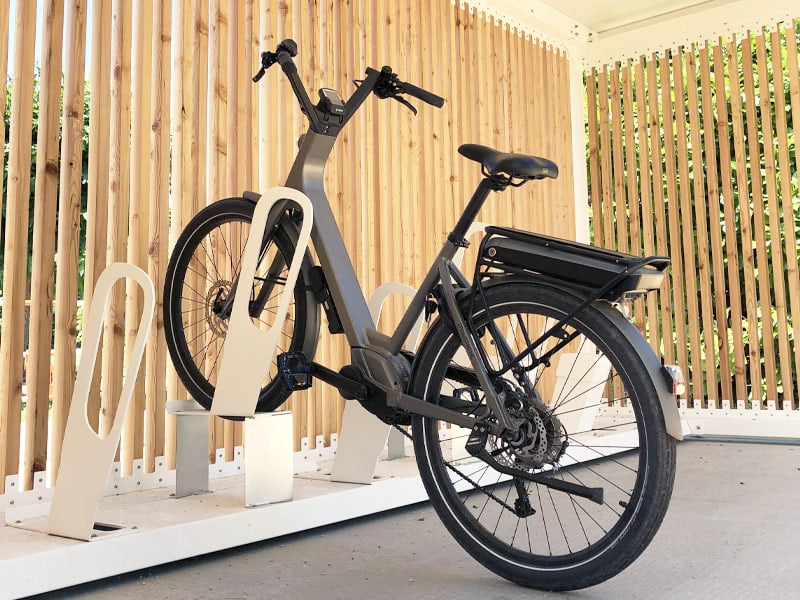Bicicletas en los portabicicletas simples ALTAO® Parco, bajo la marquesina abierta de la futura ruta ciclista de Condrieu