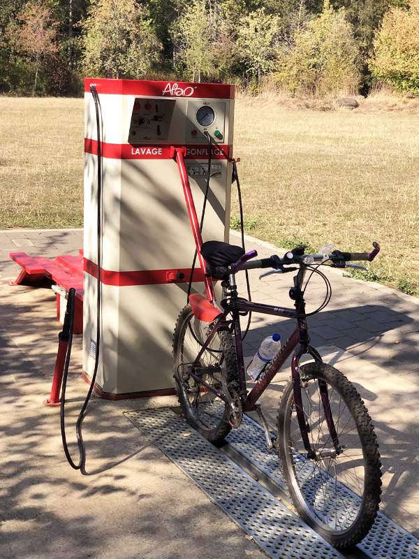 Vélo tenant debout sur un rail et avec le bras rigide accroché à la selle et sur la station de lavage ALTAO® Modulo