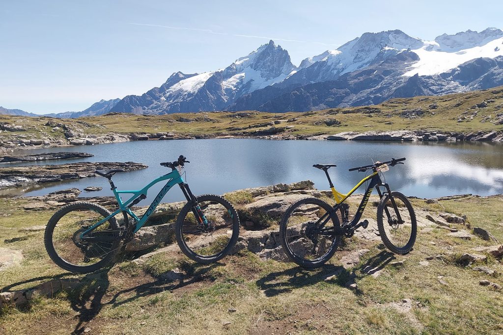 VTT devant un lac devant les montagnes de La Meije