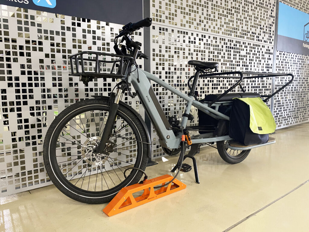 un vélo a assistance électrique longtail stationné et attaché sur un arceau vélo cargo ALTAO® Bridge