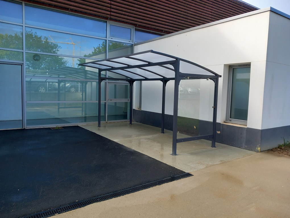 Abri ALTAO® Curve adossé à un bâtiment pour optimiser l’espace disponible